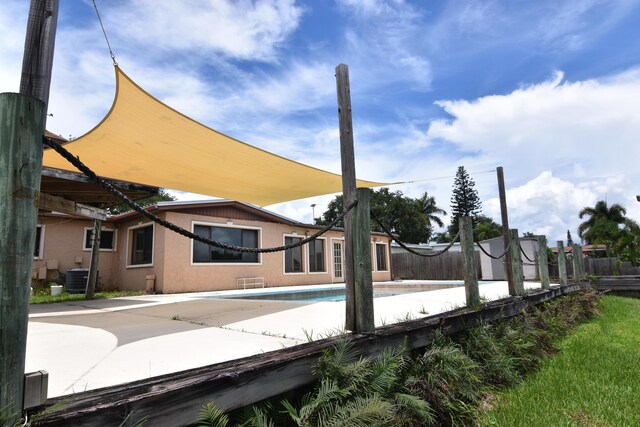 exterior space with a patio area, a fenced in pool, and central AC