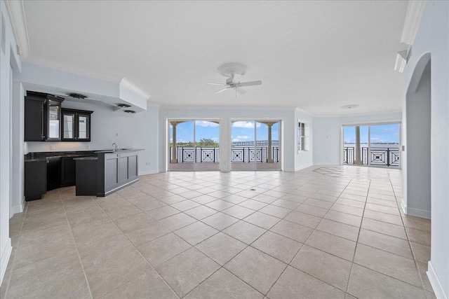 unfurnished living room with crown molding, ceiling fan, sink, and light tile patterned floors