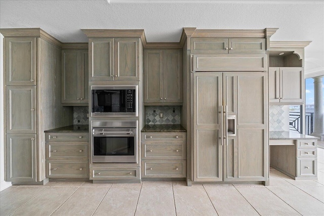 kitchen featuring a textured ceiling, built in appliances, light tile patterned floors, and decorative backsplash