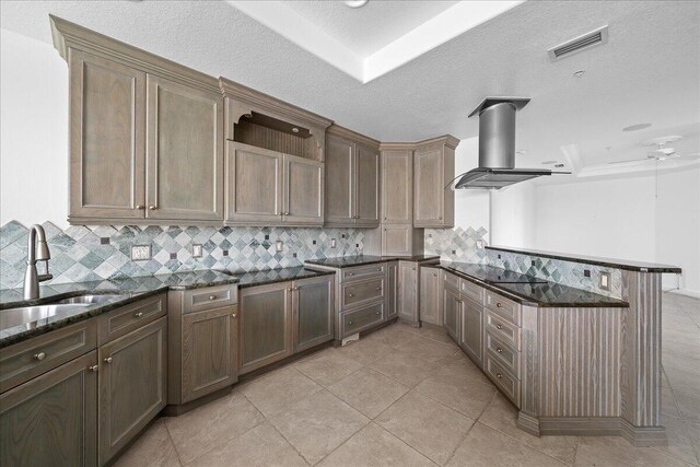 kitchen featuring ceiling fan, dark stone countertops, backsplash, and island exhaust hood