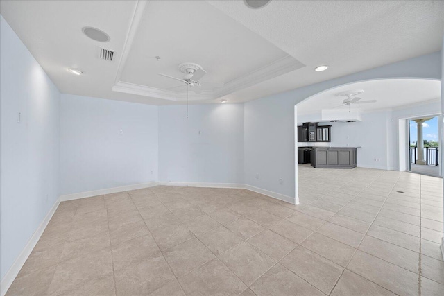 unfurnished room featuring a tray ceiling, ornamental molding, light tile patterned floors, and ceiling fan