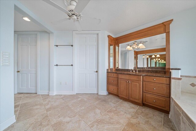 bathroom with ceiling fan with notable chandelier, vanity, a textured ceiling, and tile patterned floors