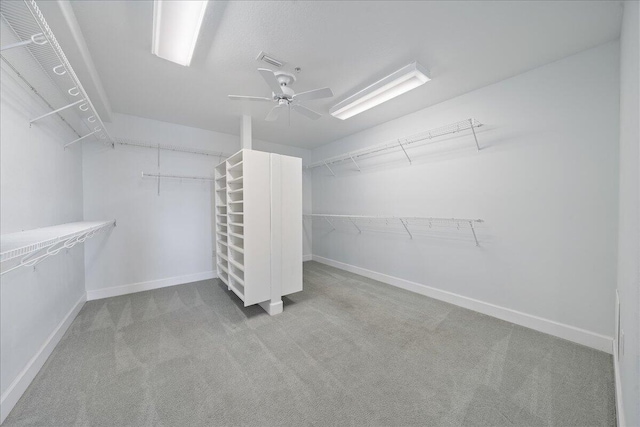 walk in closet featuring a ceiling fan and light carpet