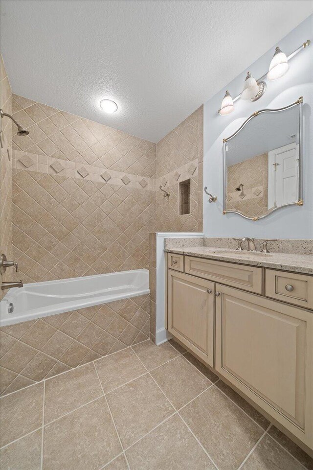 bathroom featuring tile patterned floors, tiled shower / bath, a textured ceiling, and vanity