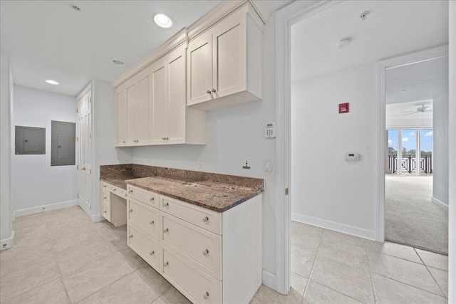 kitchen with electric panel, ceiling fan, dark stone countertops, and light tile patterned floors