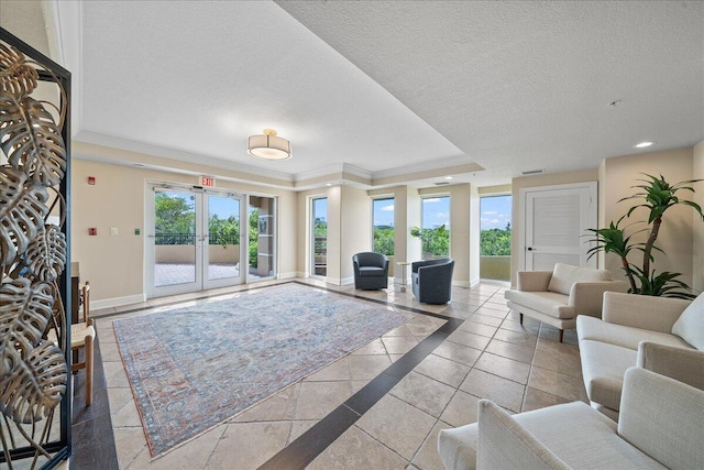 living room with a textured ceiling, a healthy amount of sunlight, a raised ceiling, and baseboards