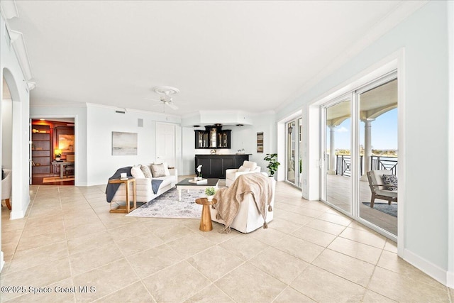 living room with light tile patterned floors, ceiling fan, baseboards, and crown molding