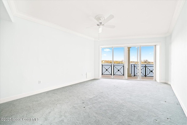 carpeted spare room with baseboards, a ceiling fan, and crown molding