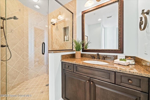 bathroom featuring visible vents, vanity, and a shower stall