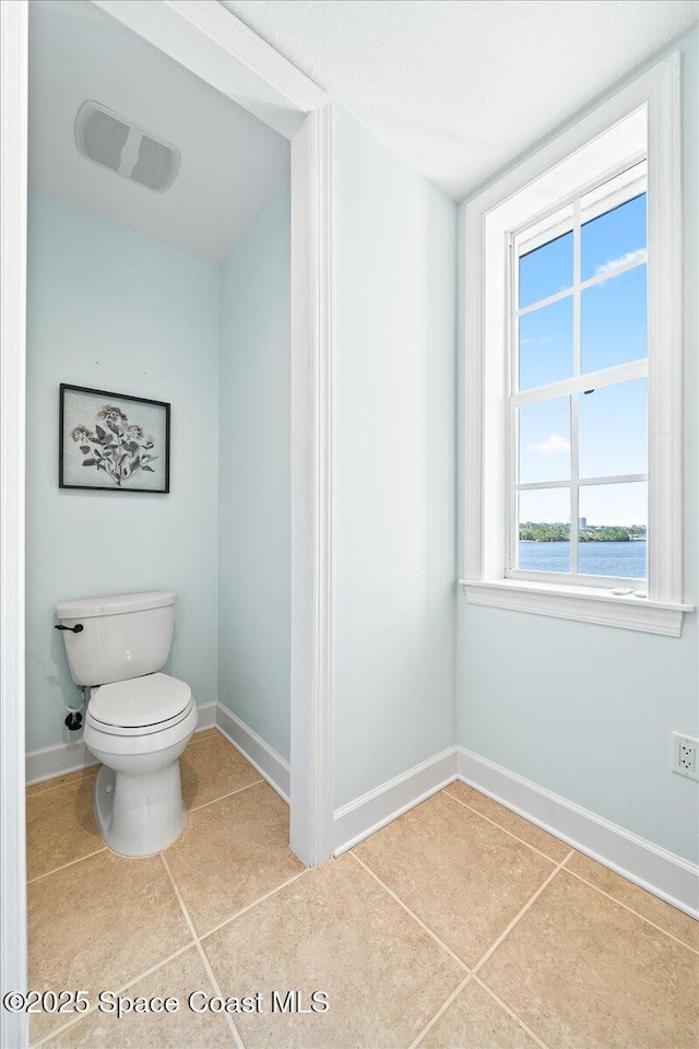 bathroom featuring a water view, toilet, baseboards, and tile patterned floors