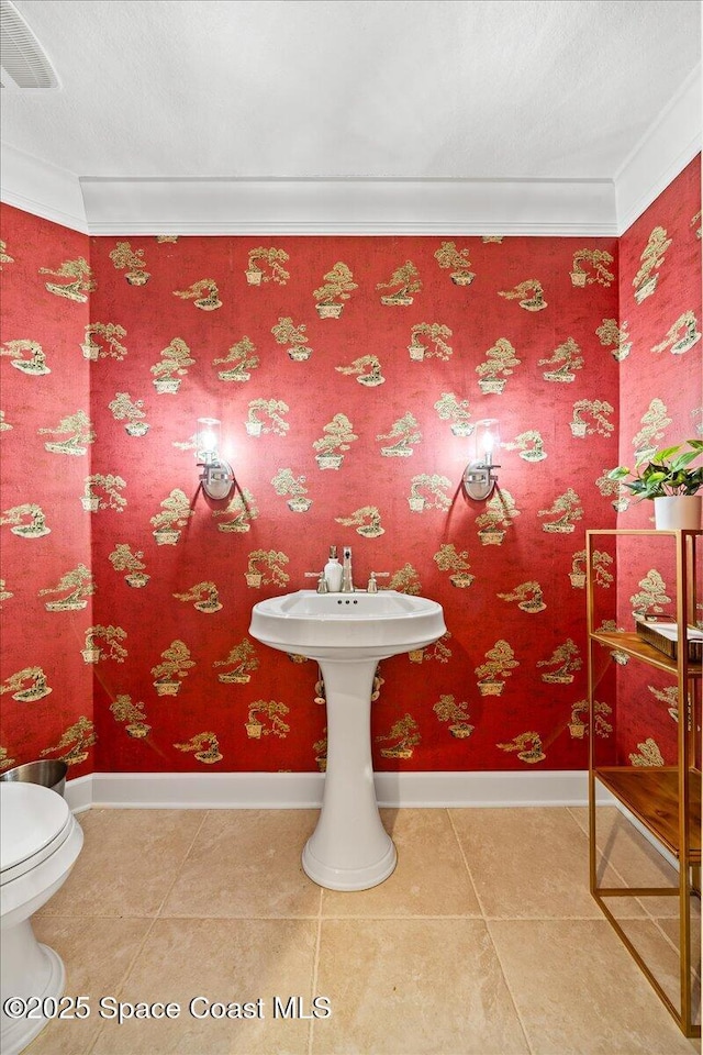 bathroom with ornamental molding, baseboards, toilet, and tile patterned floors