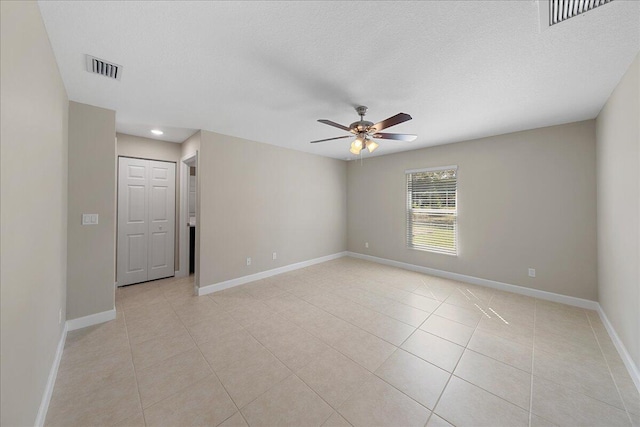 tiled spare room with a textured ceiling and ceiling fan