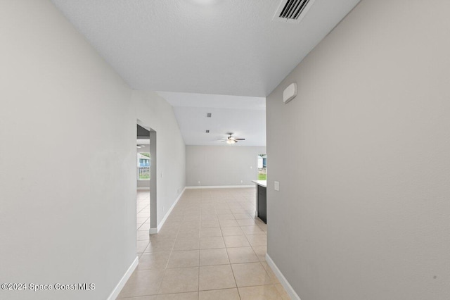 corridor featuring a textured ceiling and light tile patterned floors