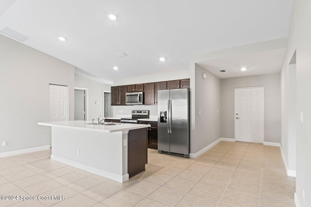 kitchen with stainless steel appliances, sink, lofted ceiling, light tile patterned flooring, and a center island with sink