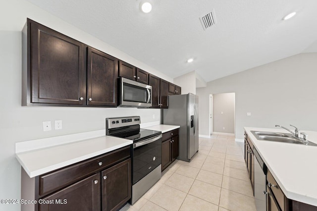 kitchen with sink, light tile patterned floors, vaulted ceiling, and appliances with stainless steel finishes