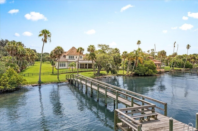 view of dock with a water view and a lawn