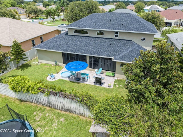 rear view of property with a yard, a patio area, and a fire pit