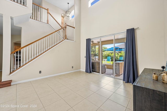 unfurnished living room featuring an inviting chandelier, a towering ceiling, and light tile patterned floors