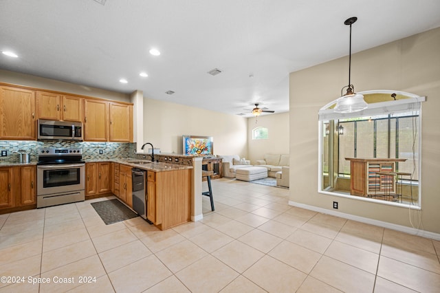 kitchen featuring backsplash, ceiling fan, stainless steel appliances, kitchen peninsula, and pendant lighting