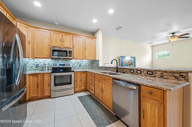 kitchen featuring light tile patterned flooring, appliances with stainless steel finishes, light stone counters, tasteful backsplash, and ceiling fan