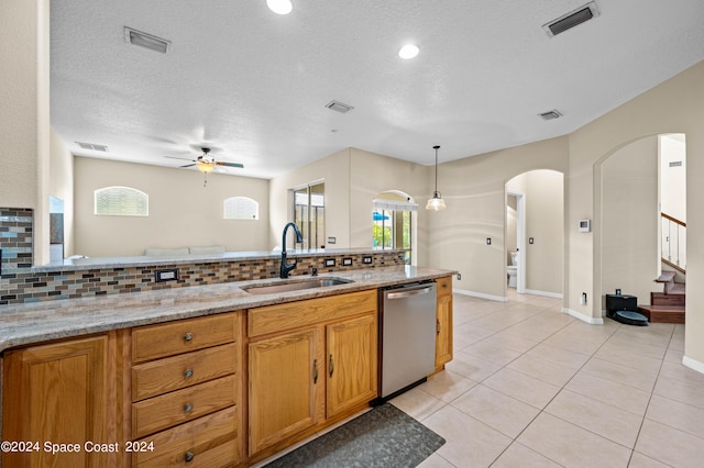 kitchen featuring light stone countertops, sink, stainless steel dishwasher, and decorative backsplash