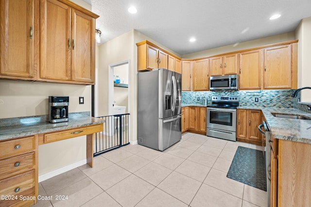 kitchen with appliances with stainless steel finishes, light stone countertops, sink, and backsplash