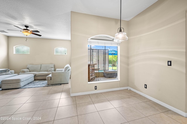 living room with light tile patterned flooring, ceiling fan, and a textured ceiling