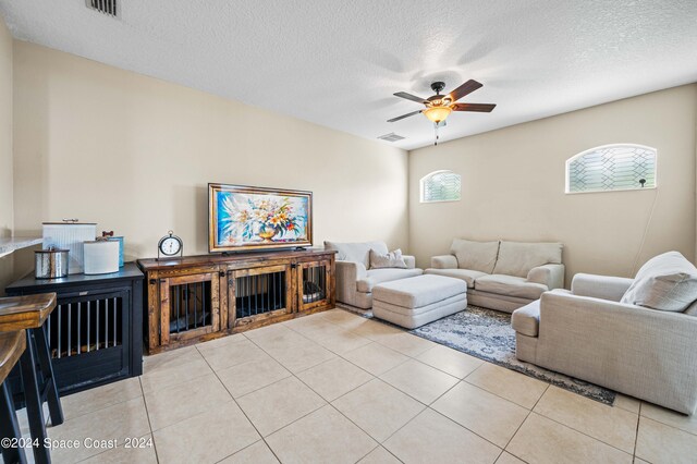 tiled living room with a textured ceiling and ceiling fan