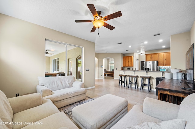 tiled living room featuring ceiling fan and a textured ceiling