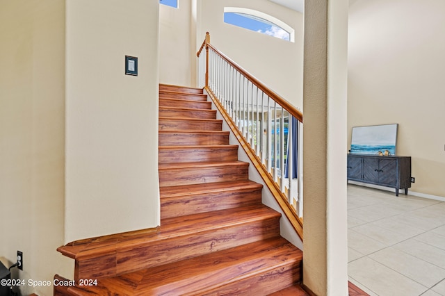 stairs featuring tile patterned flooring and a high ceiling