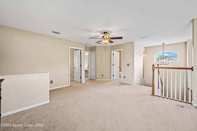 spare room with light carpet, ceiling fan, and a textured ceiling