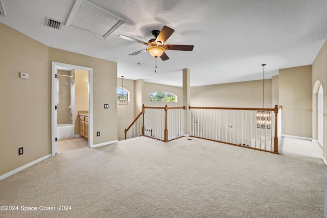 carpeted empty room featuring ceiling fan with notable chandelier and a textured ceiling