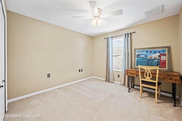 carpeted office featuring ceiling fan and a textured ceiling