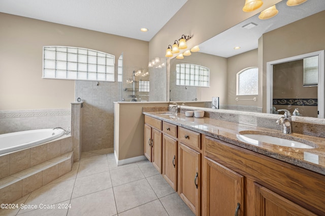 bathroom featuring tile patterned flooring, a relaxing tiled tub, a textured ceiling, and double sink vanity