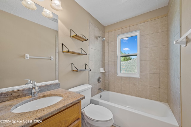 full bathroom featuring a textured ceiling, toilet, tiled shower / bath combo, and vanity