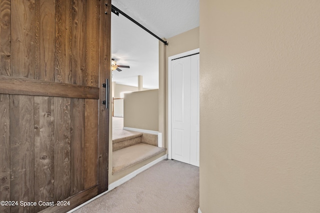 stairs with a textured ceiling, carpet floors, and ceiling fan