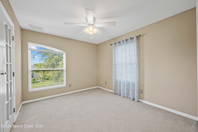 spare room with ceiling fan, light colored carpet, and a textured ceiling