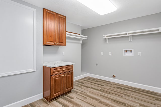 washroom with light wood-type flooring, cabinets, and hookup for a washing machine