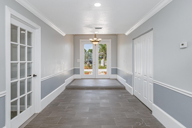 entryway with crown molding, a notable chandelier, and french doors