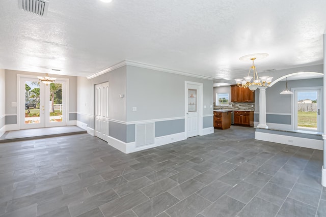 unfurnished room featuring a chandelier, dark tile patterned floors, ornamental molding, french doors, and a textured ceiling