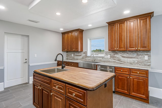 kitchen featuring a center island with sink, light tile patterned flooring, tasteful backsplash, and sink