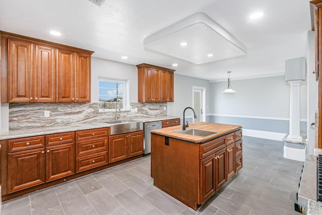 kitchen featuring backsplash, sink, decorative light fixtures, and an island with sink