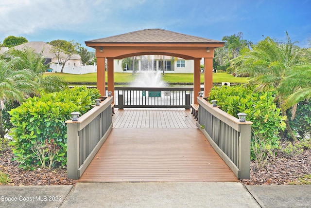 wooden deck with a gazebo, a yard, and a water view