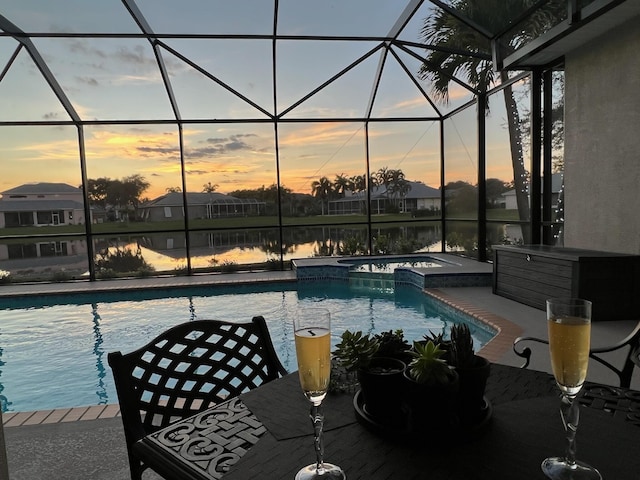 pool at dusk with an in ground hot tub, a water view, a patio area, and a lanai