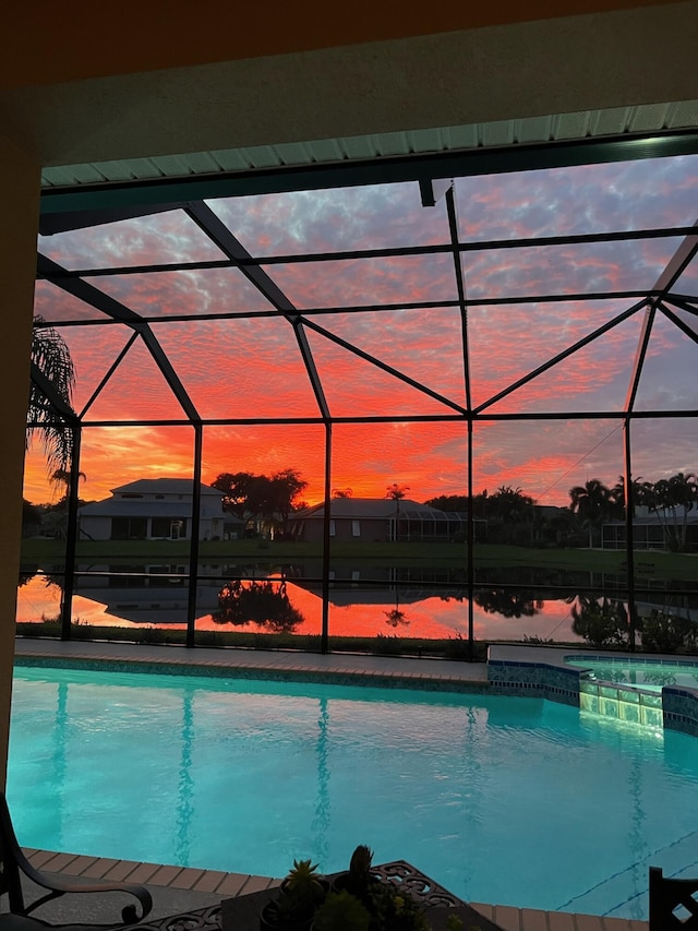 pool at dusk with a lanai and a water view