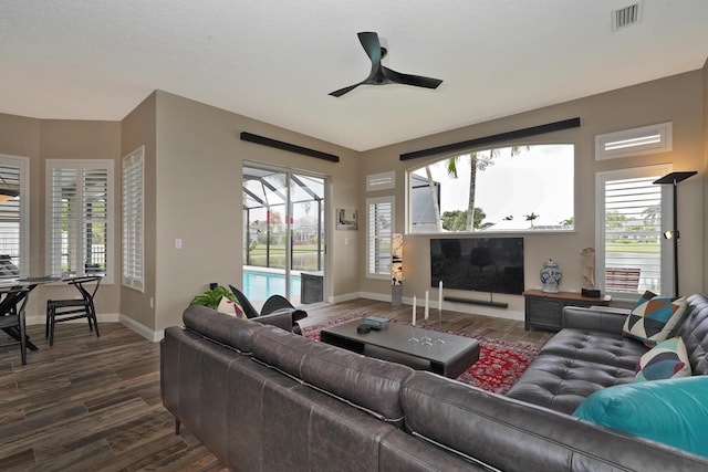 living room with a wealth of natural light, ceiling fan, and dark hardwood / wood-style flooring