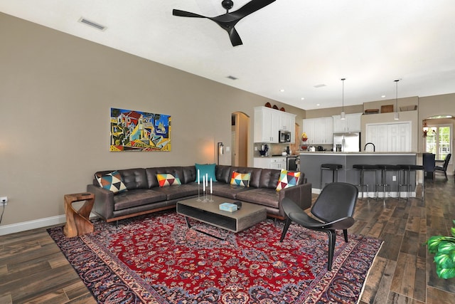 living room with dark hardwood / wood-style floors, ceiling fan, and sink