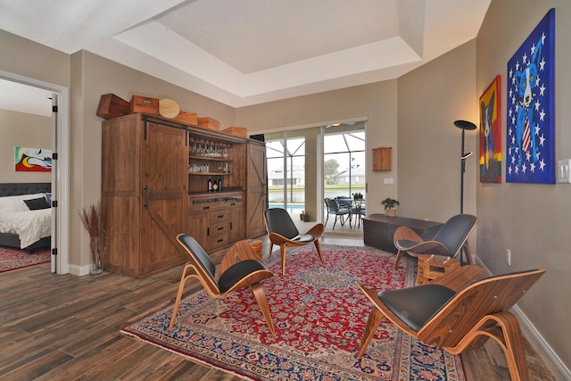 sitting room with a tray ceiling and dark hardwood / wood-style floors