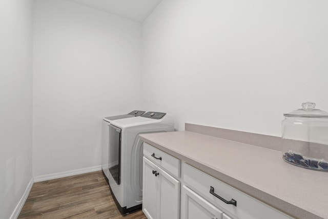 washroom with dark hardwood / wood-style flooring, cabinets, and washing machine and clothes dryer