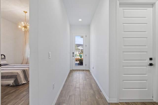 hall featuring wood-type flooring and an inviting chandelier